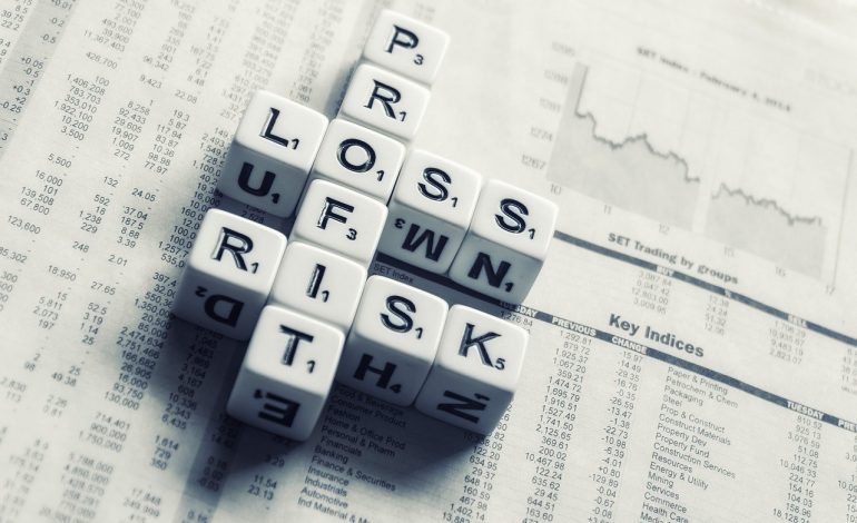 A Bunch of Cubes Arranged Over a Newspaper to Spell Profit, Loss, and Risk