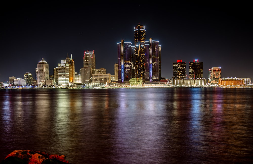 A nighttime view of the Detroit, Michigan skyline with the Detroit River in the foreground