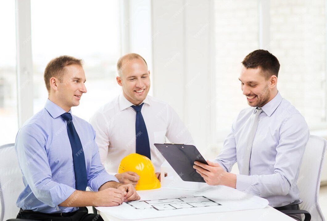 Three builders reviewing construction plans and blueprints on a job site