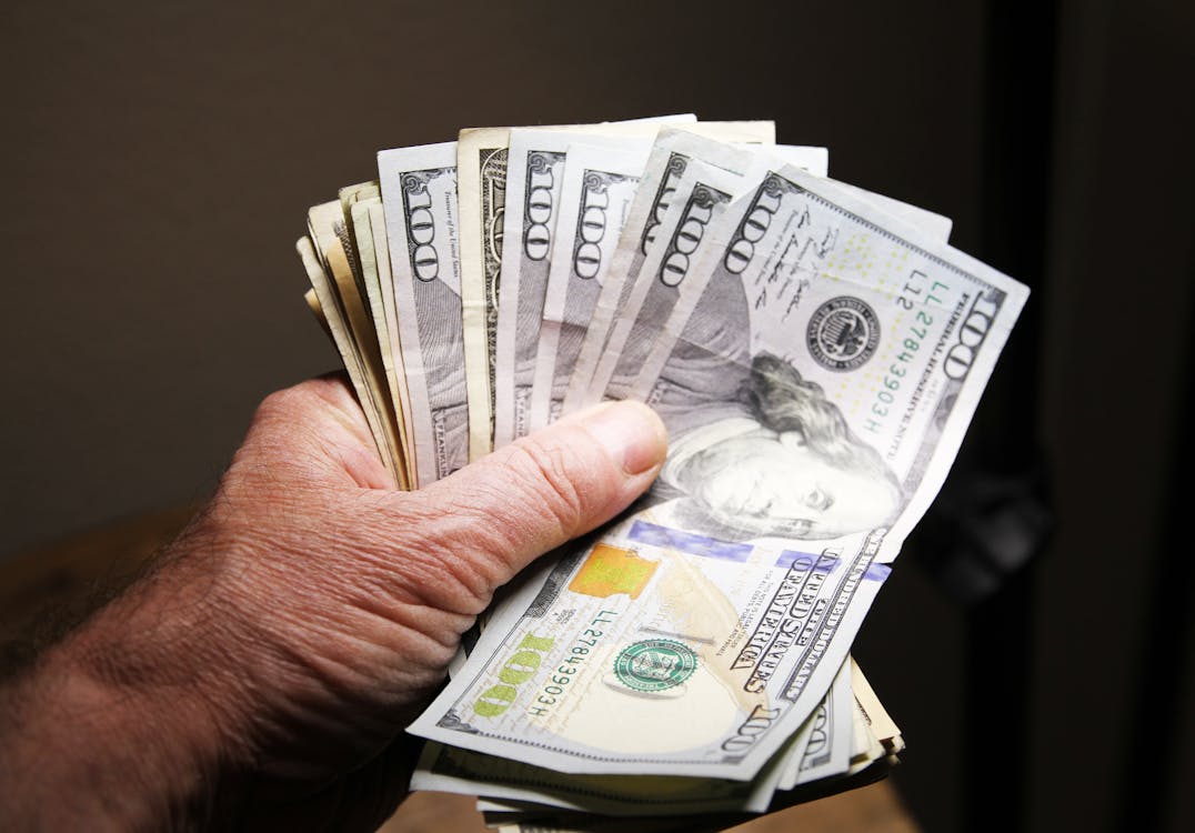A person holding 100 US dollar banknotes