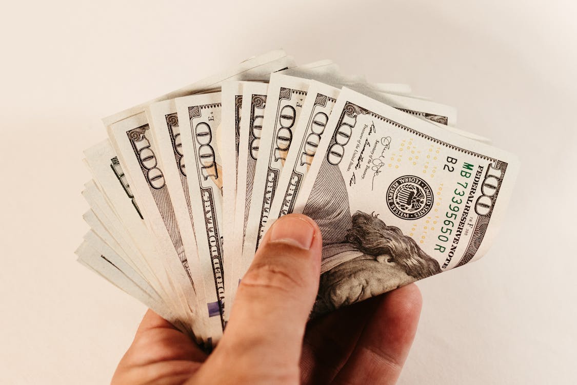 100 dollar US bills in a person’s hand