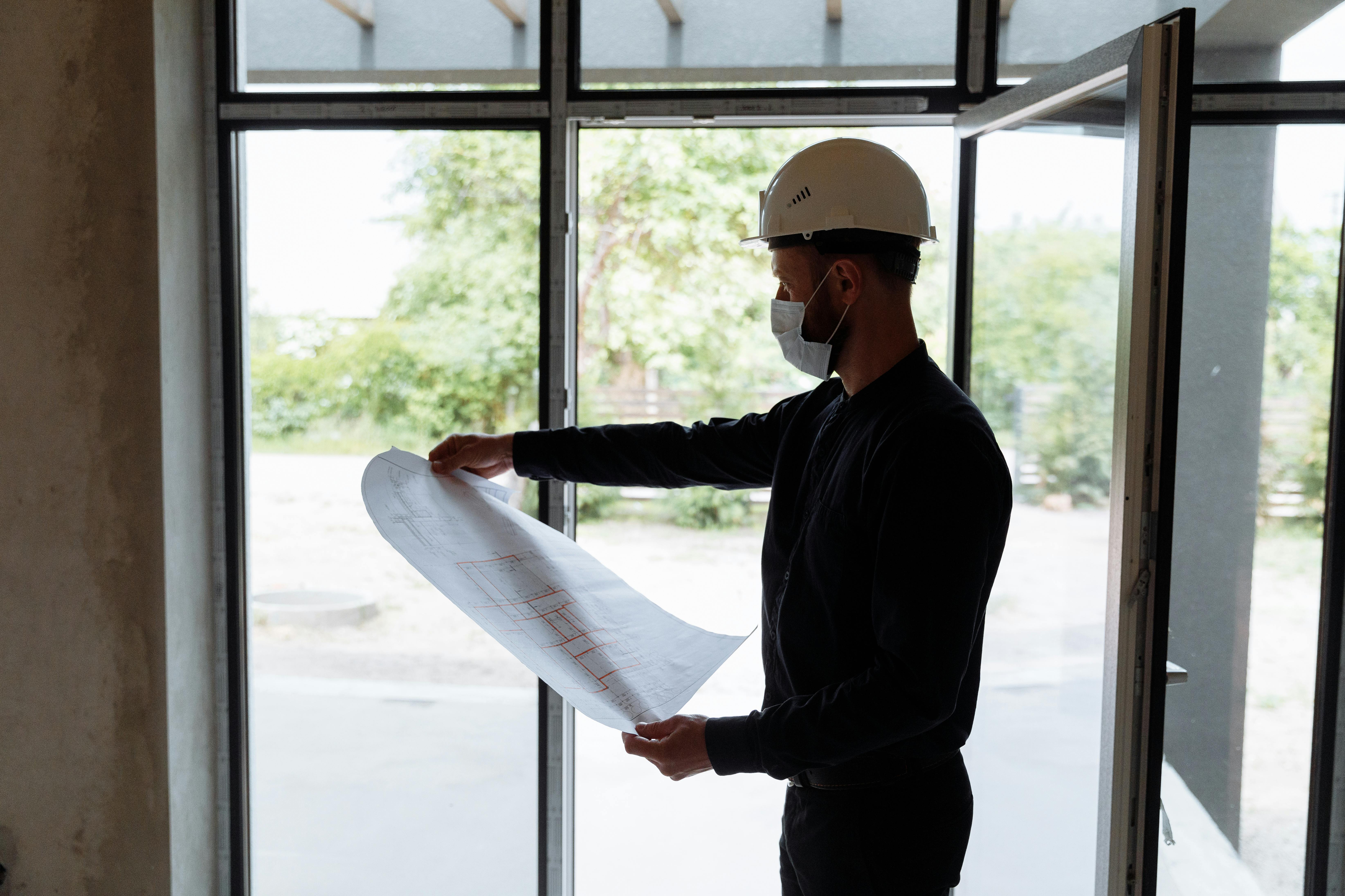 A person in a white cap looking at a construction plan at a construction site