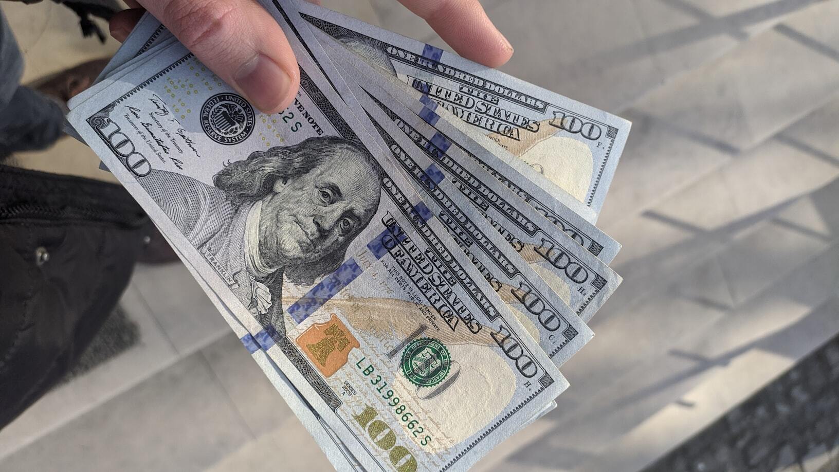A person holding 100 dollar banknotes