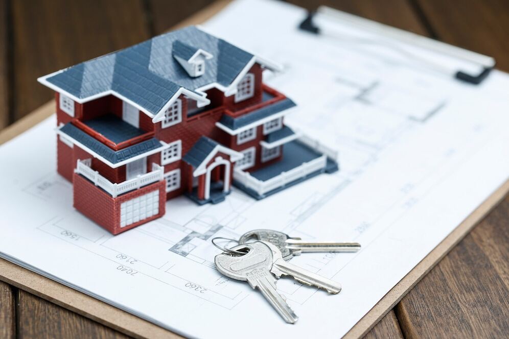 A miniature house and keys on a property map