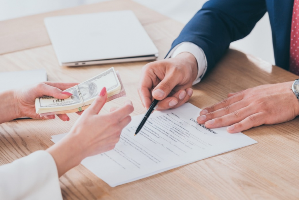  Individuals exchanging money and signing contracts, indicating a financial agreement.