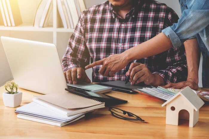 midsection-colleagues-discussing-laptop-desk-office_1048944-26016092